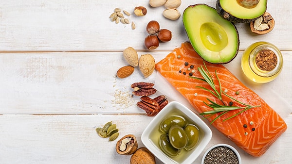 Omega-3 rich foods on the table with walnuts, salmon, avocado, olives, hazelnuts and almonds.