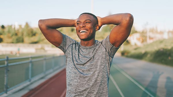 An athlete on an athletic track smiling after completing a sports session thanks to the secretion of natural dopamine.