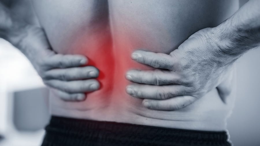 A man holds his lower back with both hands, the painful area being materialized by a red mark.