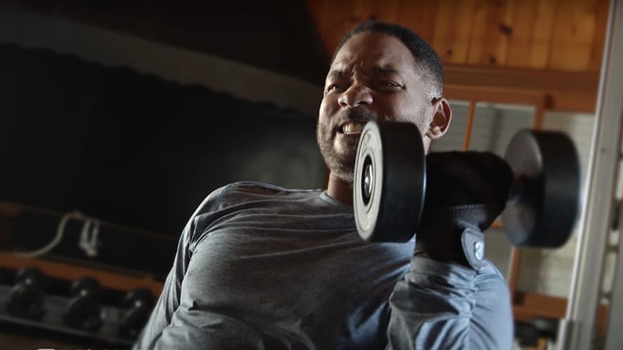 A Will Smith bodybuilding workout in which he performs the biceps curl exercise with dumbbells.