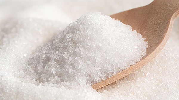 A wooden spoon in white powdered table sugar.