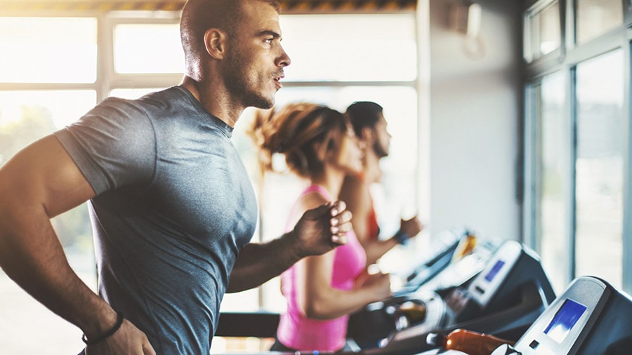 A man in a gym works out on a treadmill.