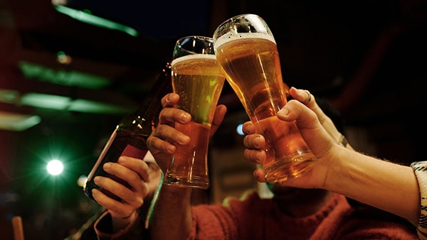 People toasting with glasses of beer in a bar.