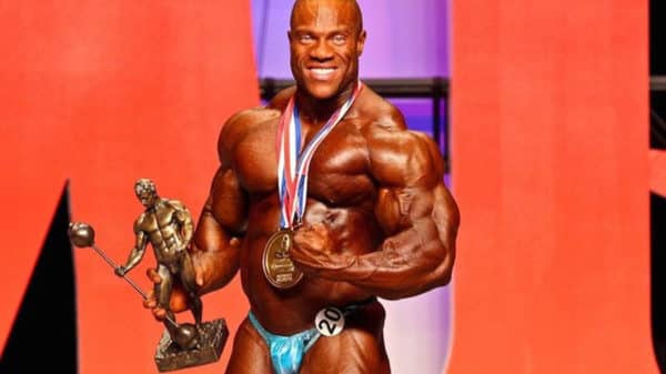 Phil Heath après avoir remporté le concours Mr. Olympia, avec sa médaille autour du cou et son trophée dans la main droite.