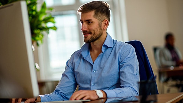 A man in a blue shirt, working at a computer, can cause a drop in testosterone.