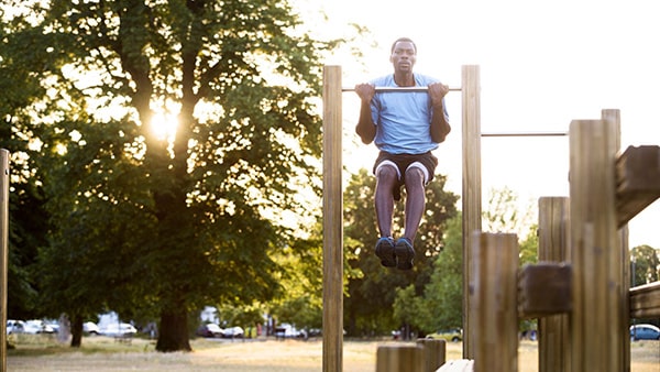 A man does pull-ups on an outdoor sports area.