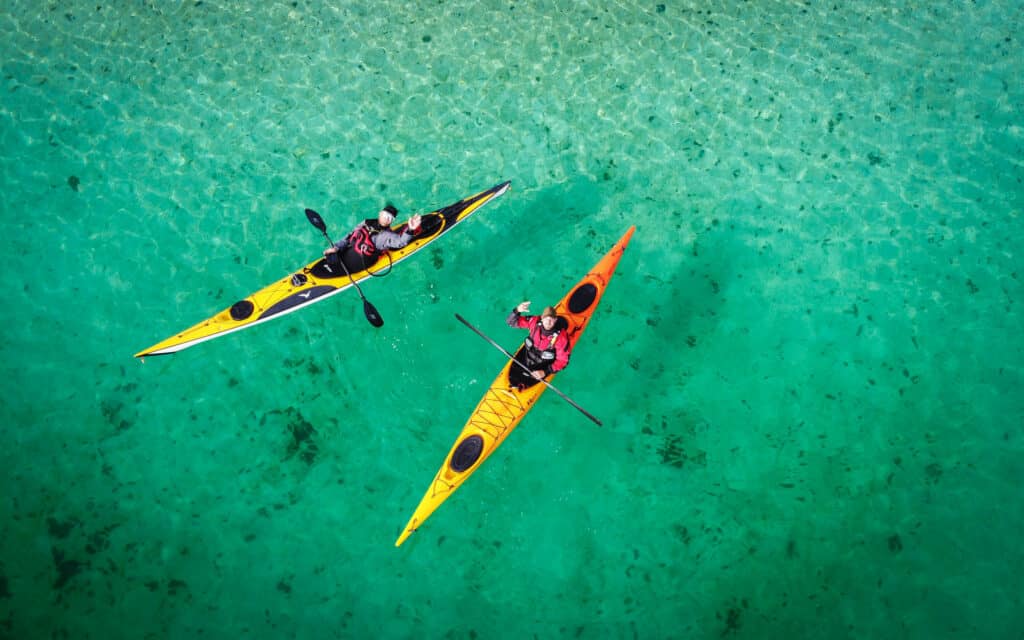 2 kayakers in Senja crystal blue water drone during a kayak expedition