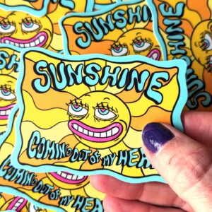 Vibrant sticker featuring a whimsical sun with a mischievous expression, surrounded by wavy yellow and orange rays. The sticker includes the playful text 'SUNSHINE COMING OUT OF MY HEAD' in bold, stylized lettering. Set against a light blue border, this quirky design adds a cheerful and humorous touch to laptops, water bottles, or notebooks