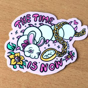 Quirky sticker design featuring a whimsical white caterpillar with a bunny face, adorned with a pink bow and heart-shaped eyes. The caterpillar is holding a gold pocket watch with a floral chain. Surrounding the illustration is the phrase 'The Time is Now' in bold, playful lettering. Set against a pastel pink background, this fun and motivational sticker is perfect for adding a touch of charm and inspiration to laptops, notebooks, or water bottles