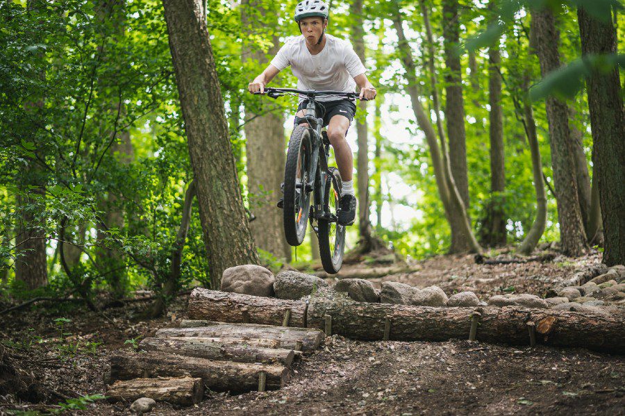 Dreng hopper over træforhindringer på mountainbike