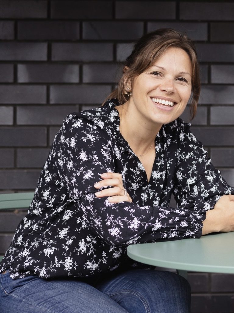 Headshot of Sarah leaning against a table