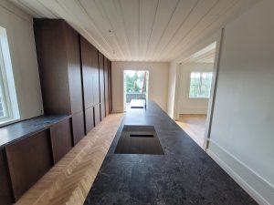 Platsbyggt kök med köksö i sten och utgång till altan – totalrenoverad villa på Lidingö.