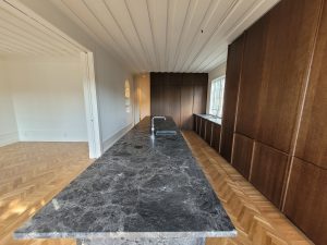 Platsbyggt kök med köksö i sten och utgång till altan – totalrenoverad villa på Lidingö.