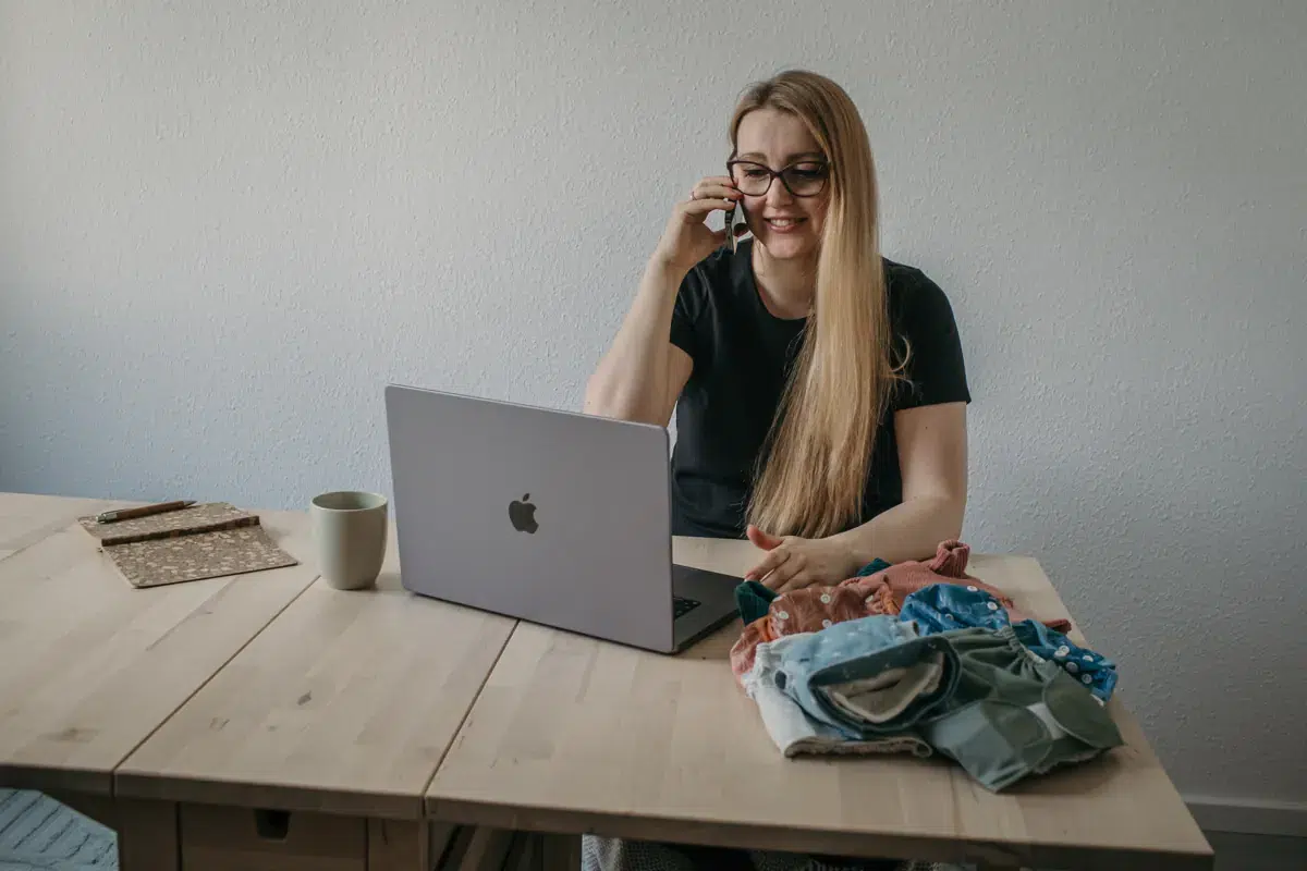 Stoffwindelberaterin am Schreibtisch mit Laptop, Telefon und Stoffwindeln