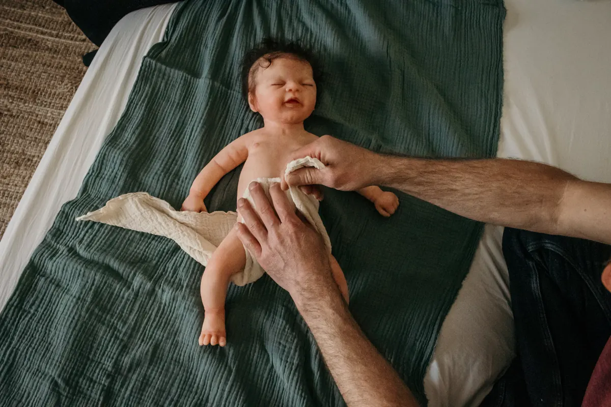 Ein Papa wickelt ein Baby mit einer Mullwindel