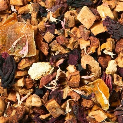 Loose herbal tea blend with dried fruit pieces, orange peels, and hibiscus blooms in warm tones.
