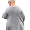 En person med kort lyst hår, iført briller og en OPSKRIFT - MODEL ASTRID - CARDIGAN MED SNONINGER, der minder om arbejde fra en strikkemaskine, ses bagfra på en almindelig hvid baggrund.