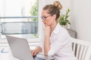 Mulher pensativa olhando a tela do notebook