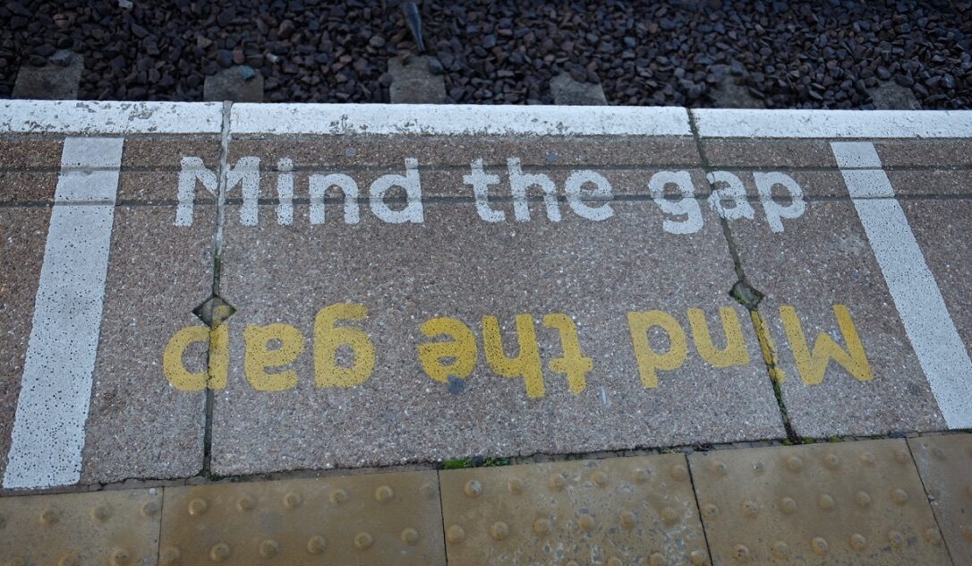 Tekst "Mind the gap" på bakken på kanten av en togplatform i London