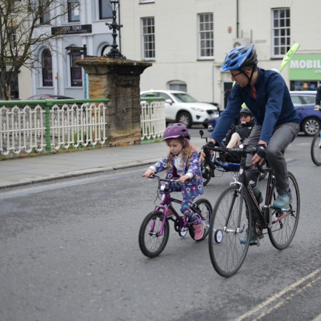 father and daughter cycling across the town bridge