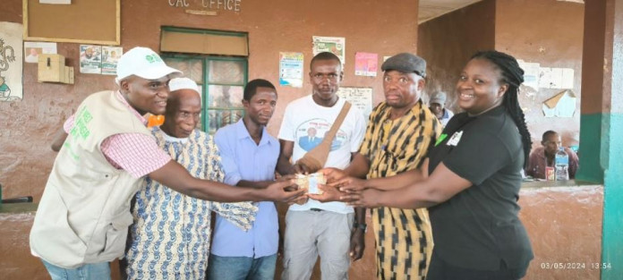 Paramount Chief of Makpele- PC SaffaTamue (2nd from right) handing over cash to participants in Zimmi Community as WHH Head of Project- Hawa Bockarie (1st from right) joins in the distribution.