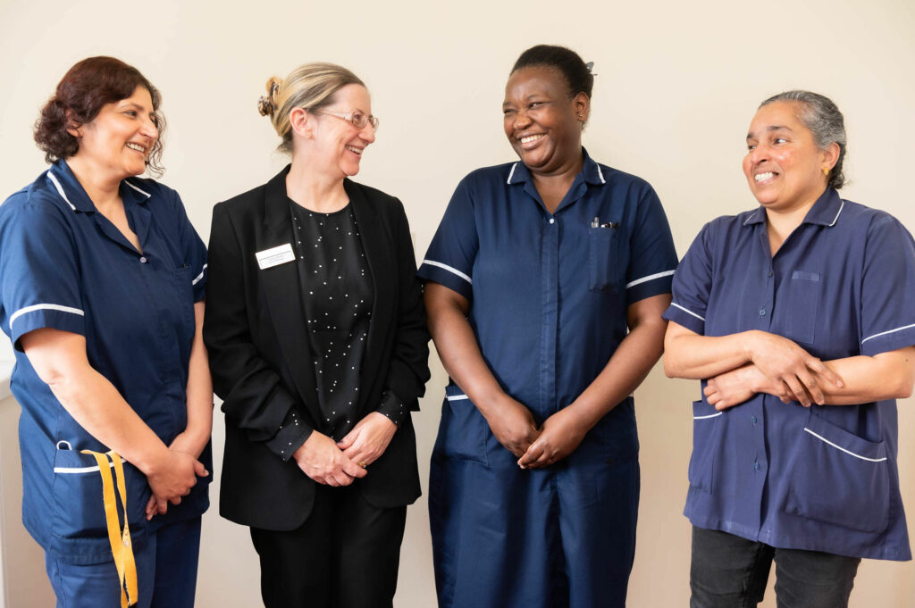 4 members of staff smiling at one another.