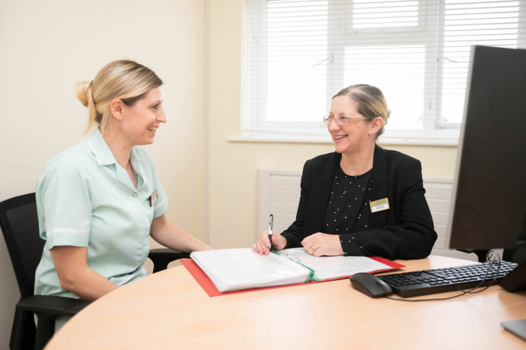Members of staff smiling whilst going through a folder together.