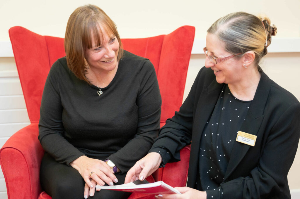 Member of staff going through a book with a middle aged woman.