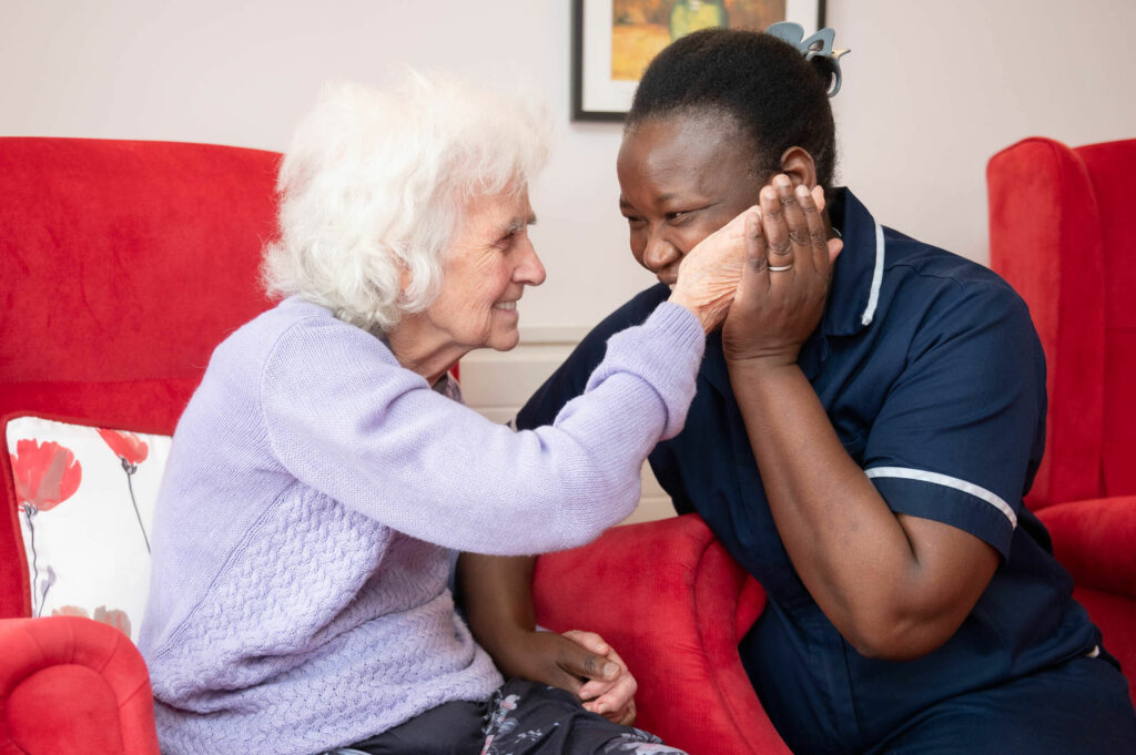 Elderly resident touching the face of a member of staff in a caring manner.