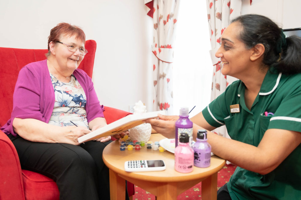 A member of staff looking at a booklet with an elderly resident.