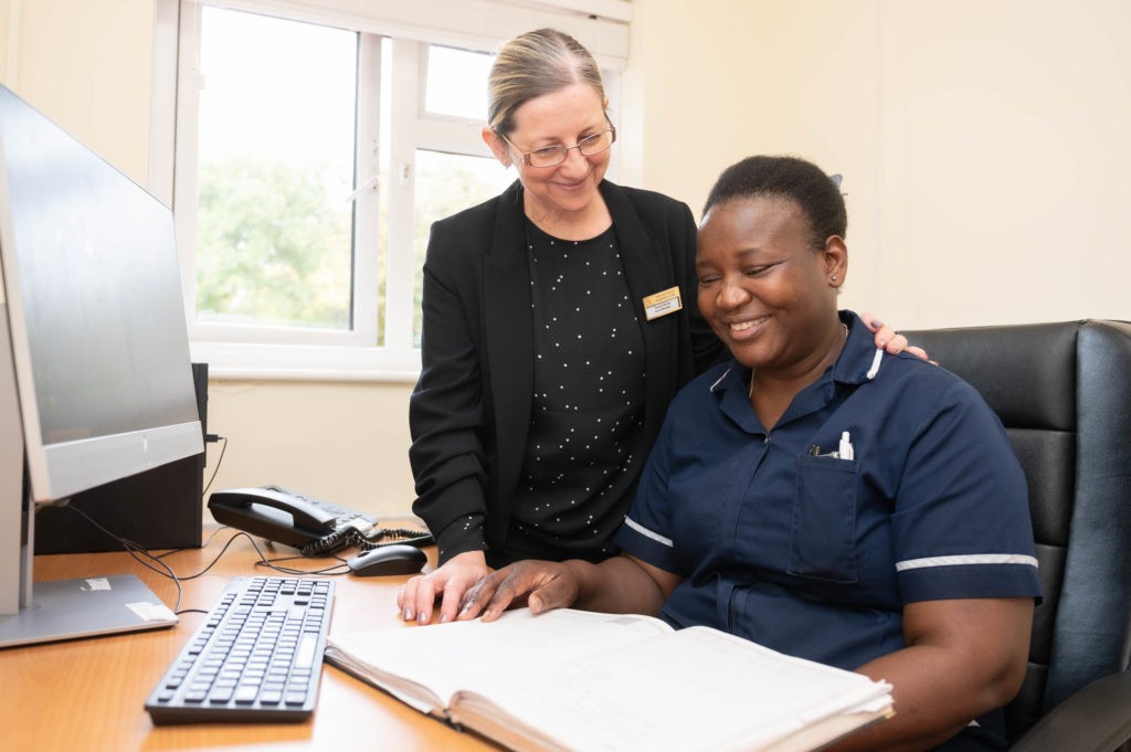 A member of staff helping another team member read/understand something.