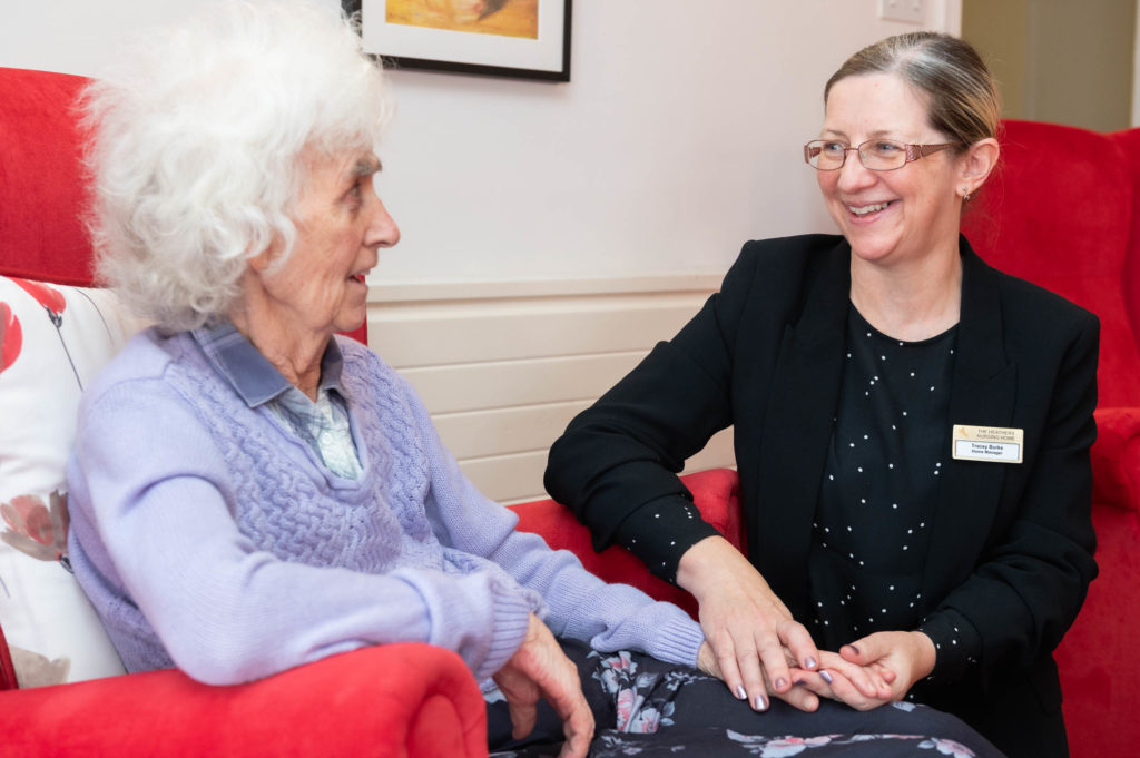 A member of staff holding hands with an elderly resident.