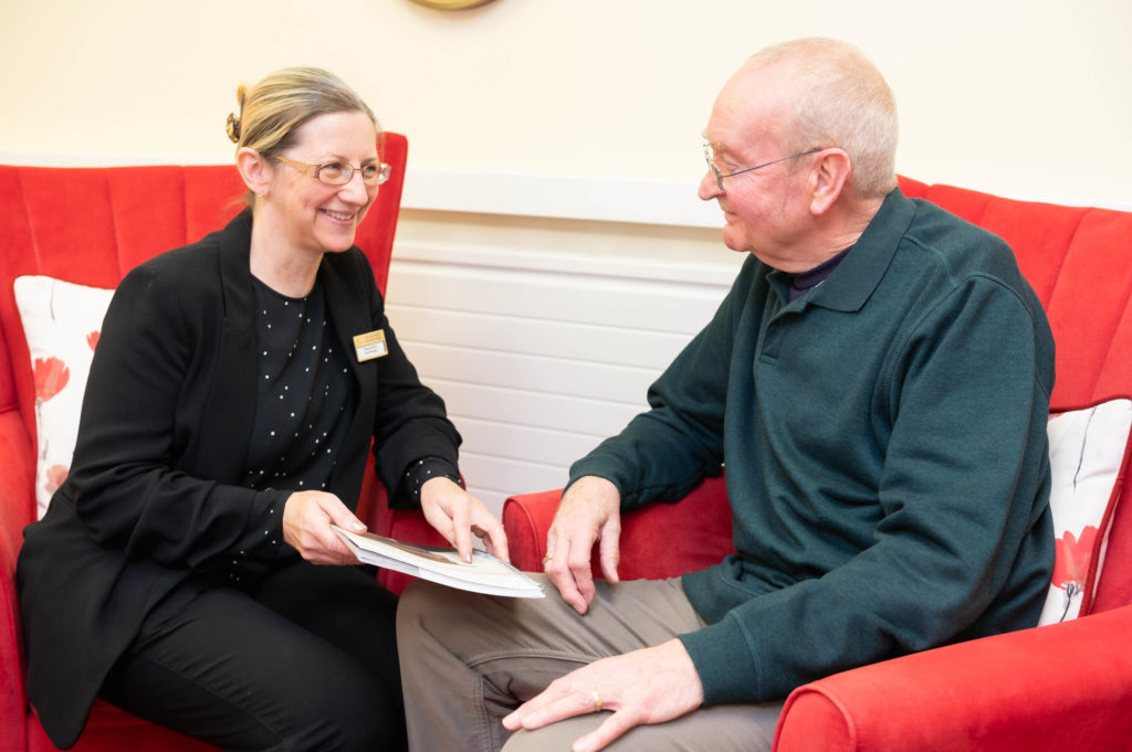 A member of staff reading something with an elderly resident.