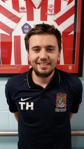 BGU Left back Toby Hatcher in front of a framed Lincoln city shirt.