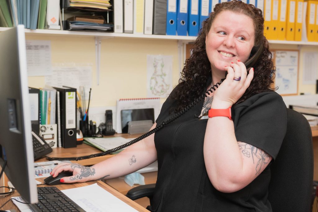 Member of staff smiling whilst speaking on the phone.