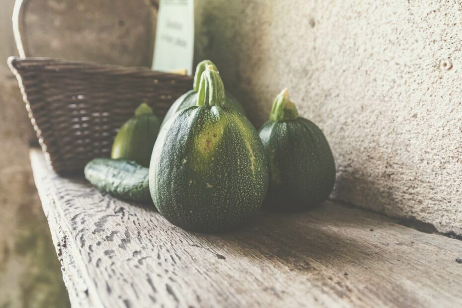 ronde courgettes, een komkommer en een mandje op een houten plank