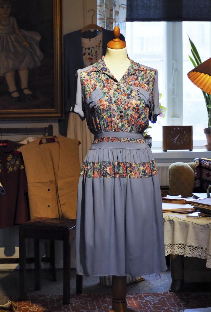 Lilla og blomstret kjole lavet af genbrugte andre kjoler fra under 2. verdenskrig i 1940'erne, meget stof blev genbrugt under krigen, originalt tøj fra museet Tidens Samling, museum for klæder, form og bolig i det 20. århundrede, Kulturmaskinen, Farvergården, Brandts Klædefabrik, Odense