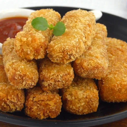 Crispy eggplant fingers arranged on a plate with a dipping sauce on the side