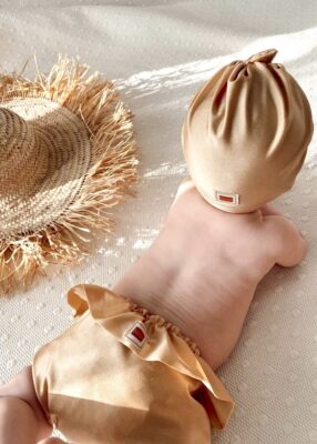 Set Lycra Goud dragend door een baby. Ideaal voor een dag in het water. Verkrijgbaar in de webshop.