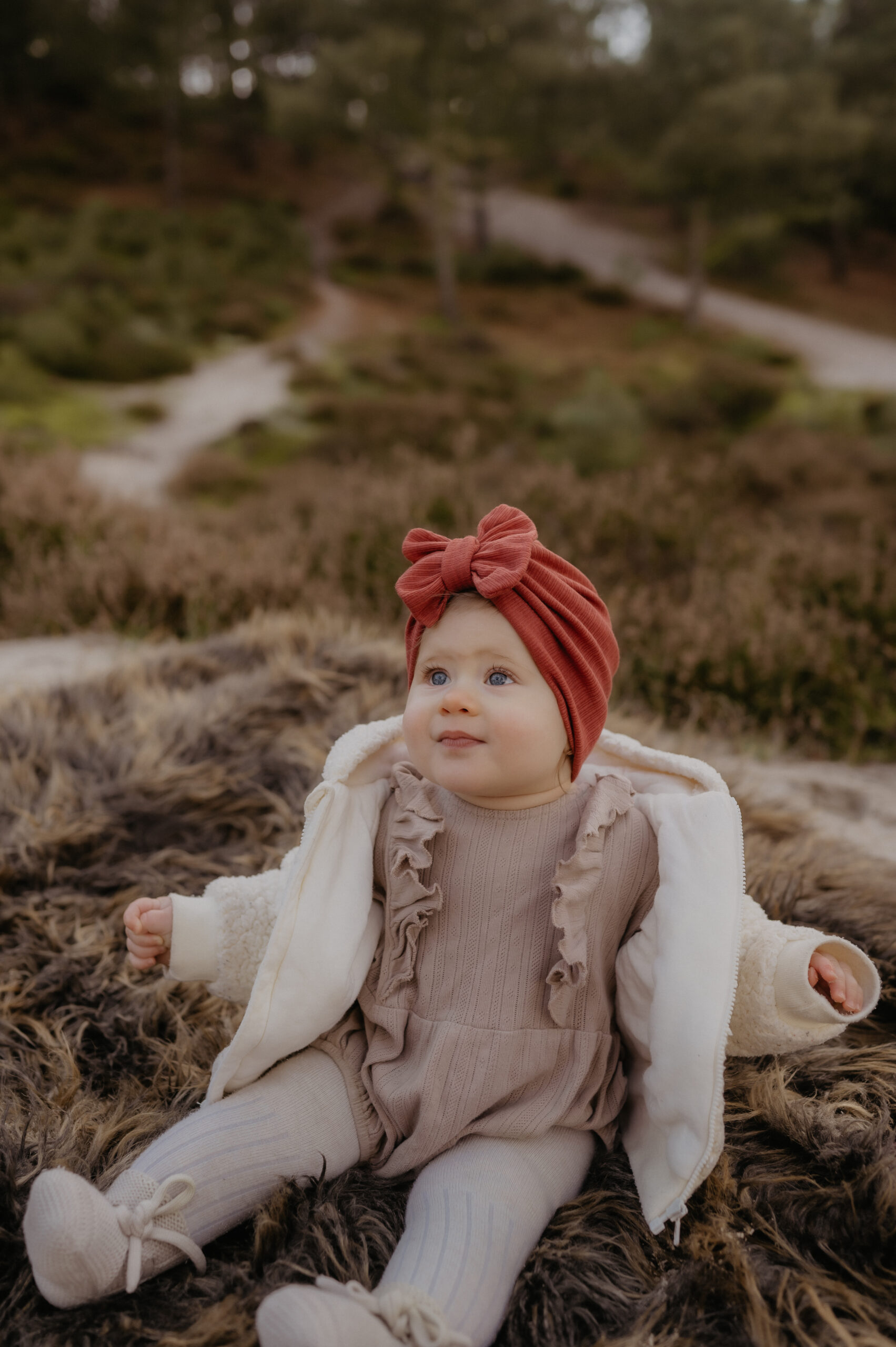 Kindje in de duinen met een Turban baby mutsje op haar hoofd.