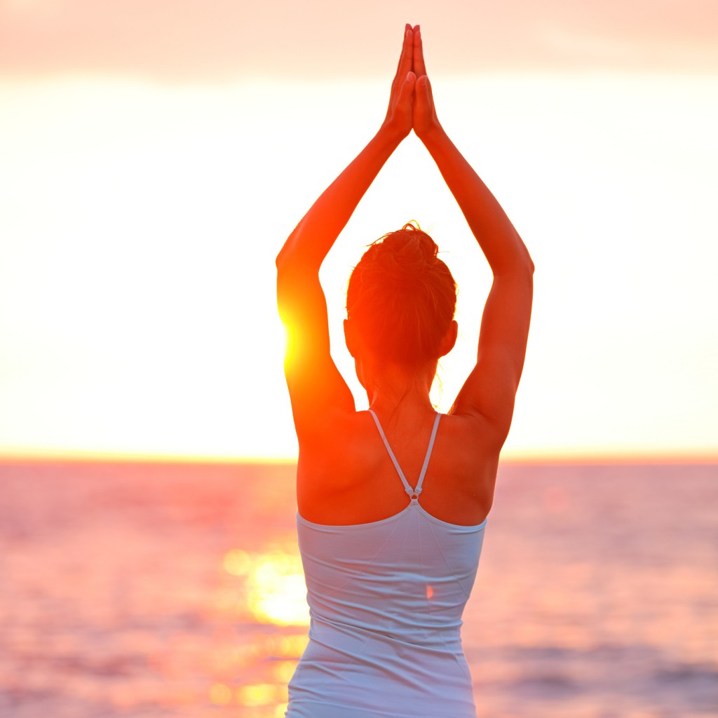 Meditation Yoga woman meditating at beach sunset or sunrise relaxing in yoga pose. Serene relaxed female yoga instructor in calm nature sea scene. From Big Island, Hawaii, USA.