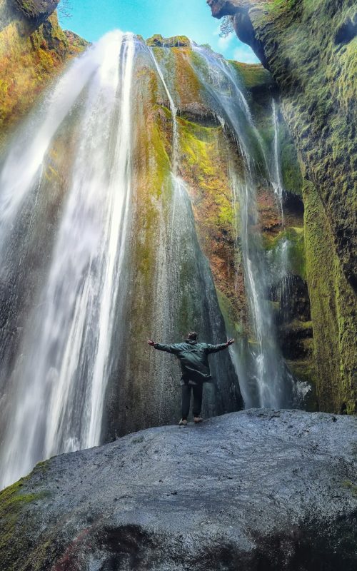 Traveler stunned by Gljufrabui waterfall cascade in Iceland.