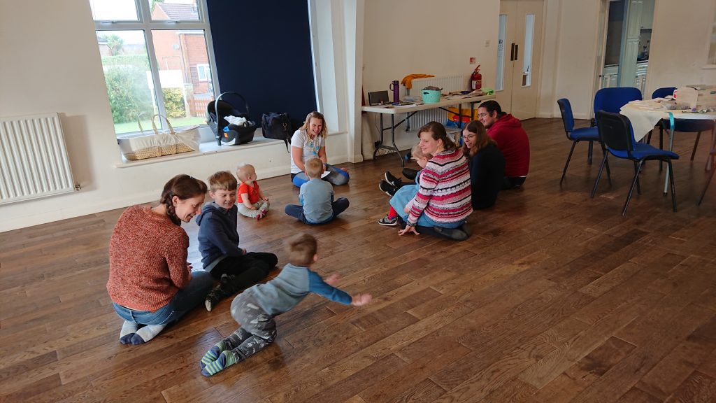 Children's sitting down listening to teacher explain scripture.