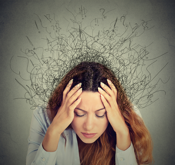 Blog: Hvad sker inde i hovedet? Kvinde holder sig til hovedet. Streger bag ved hovedet der symboliserer kaos.