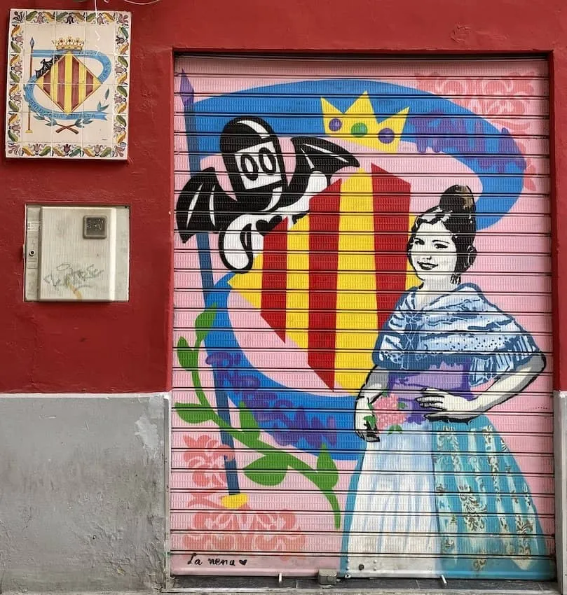 Street art mural on Valencia shutter featuring stylized woman and Valencia shield