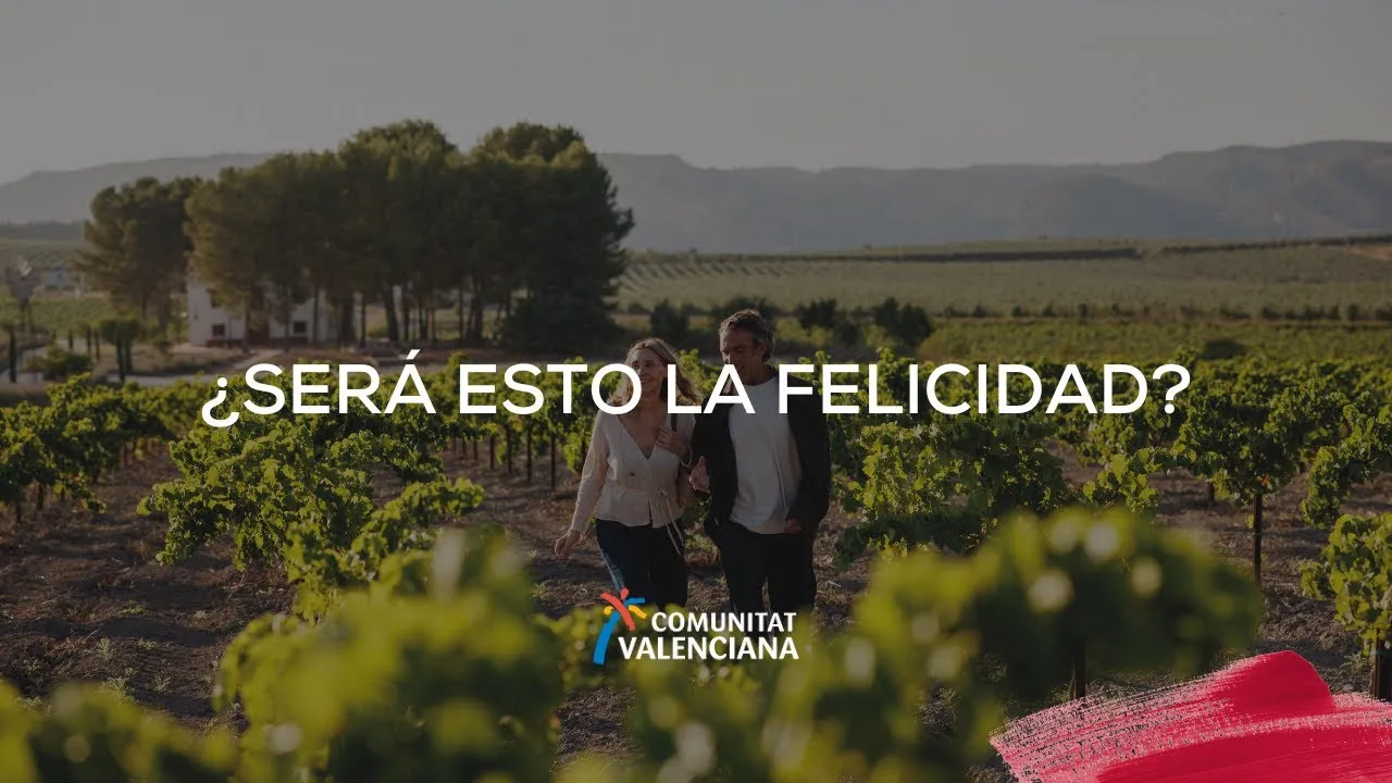 Smiling couple walking hand-in-hand through vineyard rows at sunset in the Valencian Community, evoking happiness and rural tranquility