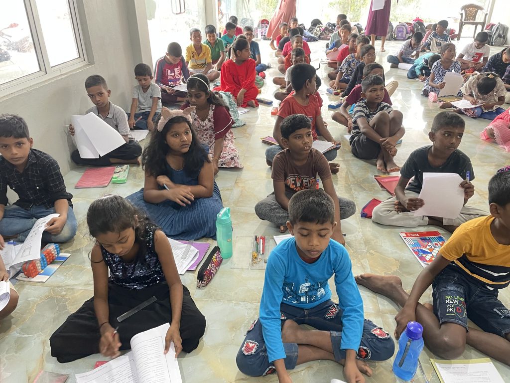 Børnene sidder på rækker mens de lytter til seminaret