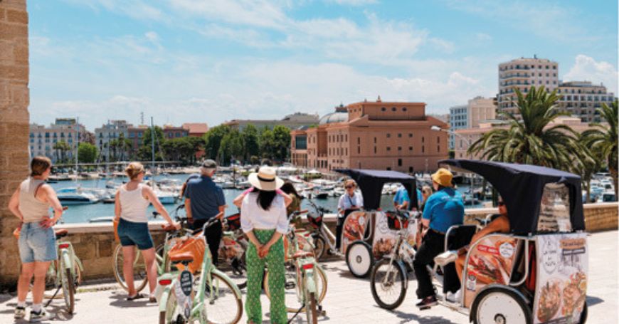 Group of people on a bike tour in Bari stop to admire the view of the teatro Margherita, one of the best things to see in Bari