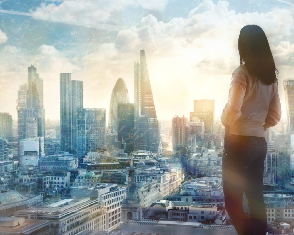 Young woman looking over the City of London at the early morning time. Future, new business opportunity and business success concept.