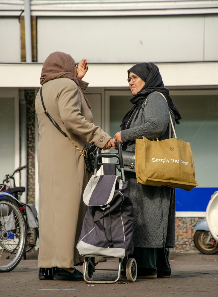 2 moslim dames die tijdens het boodschappen doen een praatje maken met elkaar
